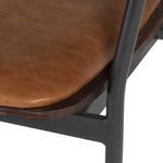 Close-up of the desert leather seat texture and black metal frame detail on Gianni Shell Dining Chair