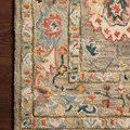 Close-up corner of Padma Grey / Multi Rug on dark hardwood floor highlighting hooked wool texture and vibrant border colors