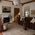Milena rug in a living room with brown sofa, cream armchair, wooden side tables, and beige walls with natural light