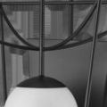 Close-up of milky white glass globe with black cap and thin metal support of Rochefort sconce