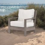 Laguna Club Chair set on sandy beach with calm ocean waves and low dune grasses in background