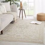 Rug styled in a bright living room next to light gray sofa and round woven pouf