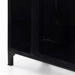 Close-up detail of black metal cabinet door panes and frame elevated on short legs