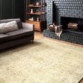 Rosette Sand / Ivory Rug shown in a cozy living room with dark brick fireplace and gray sofa