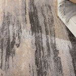 Close-up angled view of rug surface under sofa showing detailed abstract pattern and shadow play