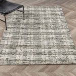 Full rug view styled in room with black chair on herringbone wood floor