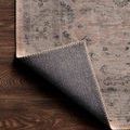 rug corner flipped up exposing dark grey woven backing and stitched edge detail