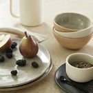 Salt jar featured on marble countertop next to small black dish and spoon with peppercorns