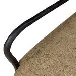 Curving angle of hammered metal armrest showing seam where frame meets upholstery
