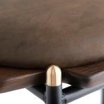 Close-up of brown seat cushion texture and brass cap detail on black metal frame corner