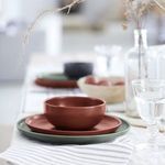 Artichoke plate with rust-colored matte bowl, styled on striped cloth alongside glassware and dried botanicals
