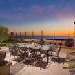 Outdoor dining scene at sunset featuring Provence Dining Chairs around glass table with ocean view