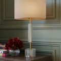 Side angle of Deville Table Lamp showing clear optic crystal cylinder midsection and antique brass finish stem