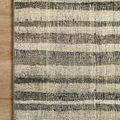Close-up of Humphrey Natural / Moss Rug corner lying flat on light wood flooring