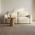 Callie Sofa staged in bright room with wood flooring, beige rug, and small round wooden side table with decorative vase