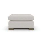Square ottoman fully upholstered in light textured chenille with braided leather welt, fluted silver shadow legs, and dark...