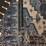 Close-up of the woven texture beside a black strap chair leg showing detailed pattern in blue and gray.