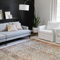 Vintage style rug in a modern living room with light gray sofa, white armchairs, and a black accent wall