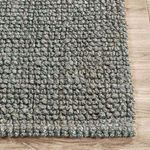 Corner of rug on wood floor showing woven edge detail and fiber texture