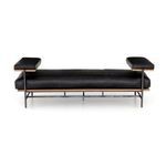 Angled close-up emphasizing leather upholstery smoothness and wooden frame between cushions