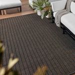gray and brown striped rug in outdoor setting under furniture with plants and throw