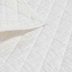 Close-up of quilt's soft cotton fabric and detailed diamond stitching texture