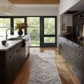 Long runner rug styled in modern kitchen with black cabinets and wood floors
