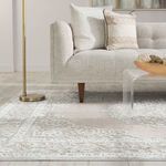 Side angle of rug beneath sofa legs with gold floor lamp and patterned cushions