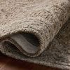 Rolled edge of rug highlighting its thickness and wool texture on hardwood floor