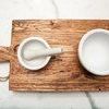 Close-up top view featuring wood grain texture with white ceramic mortar and pestle and bowl