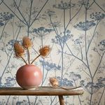 Close-up of Wild Chervil wallpaper behind rustic bench with terracotta vase and dried teasel flowers