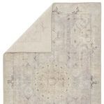 Back side of rug folded over showing reverse weave and muted color palette