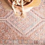 Macro shot of rug surface featuring faded geometric motifs and soft textured pile in pastel shades.