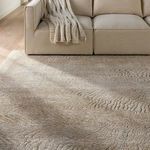 Close crop of the rug under a beige sofa with knit throw showing intricate texture and animal stripe detail
