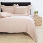 Amber-colored Vancouver Coverlet laid on queen bed with matching pillows and textured woven fabric