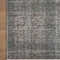 Close-up of rug corner highlighting flat weave texture and detailed plaid pattern on hardwood floor