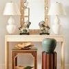 Two Fulton Vase Lamps flanking carved mirror on console table styled with oriental figurines and decorative accessories