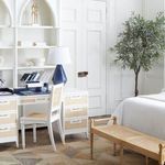 Side view of the side chair in a bedroom setting next to a white desk and decorative objects