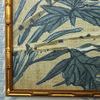 Close-up of blue and green leaves with visible linen texture and bamboo-style gold frame corner