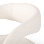 Close-up of the curved arm and backrest showing the textured off-white fabric upholstery.