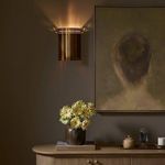Rialto Sconce shown in room setting with sideboard, vase with flowers, and artwork, illuminated on wall