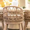 Single Dana Rope Dining Chair rear view with white floral centerpiece on dining table in soft indoor light