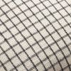 Close-up revealing textured fabric and detailed black grid stitching on ivory pillow surface