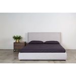 Centered Luzon bed with dark bedding and pillows against white wall in simple bedroom