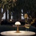 Promenade brass lamp lit on round marble table with two glasses of white wine on side
