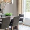 Homage Beige / Grey Rug styled in dining room with grey chairs, wooden table, large window, and beige curtains