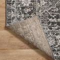 Rolled corner flipped up showing rug backing and edge binding on soft polyester weave