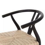 Close-up of smooth rounded black teak armrest above woven seat