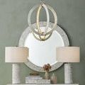 Chandelier hanging in living room setting above mirrored console table with matching lamps and decor