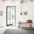 Bellamy Lagoon Rug shown in a bright white room with wooden beams, placed under natural light near an open door